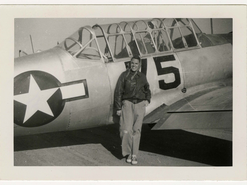 Alberta Hunt Nicholson standing in front of a fighter jet with the number five and a big star at the front. Nicholson is dressed in pilot's attire.