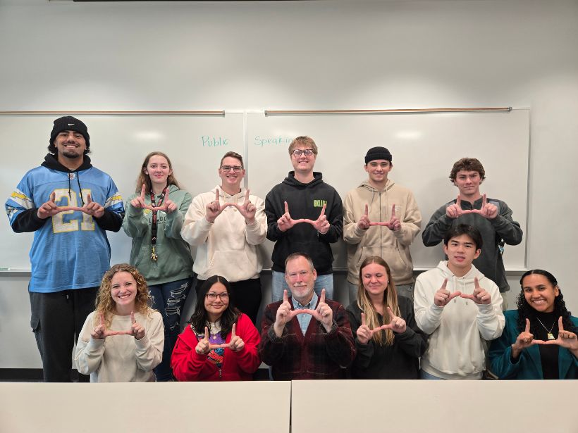 Librarian Dale Larsen surrounded by several university students flashing the U