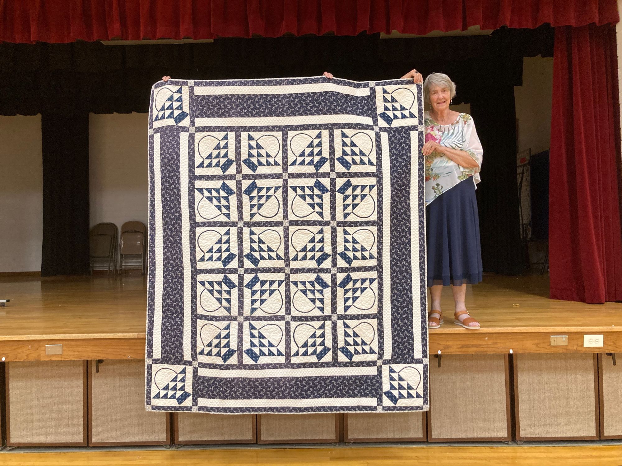 a woman holds up one of the Utah Quilts featured in the Utah Heritage Quilts Collection