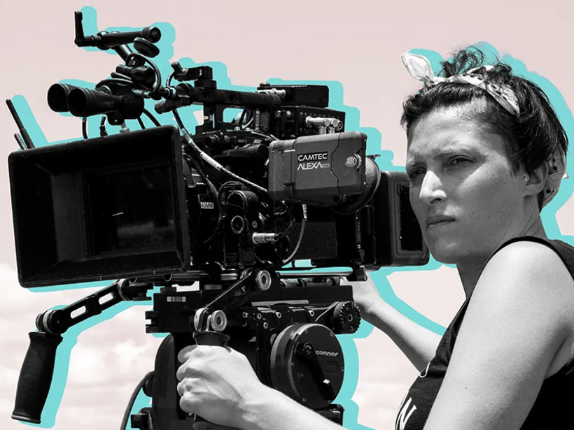 A woman with a bandana in her hair using a large camera for making movies.