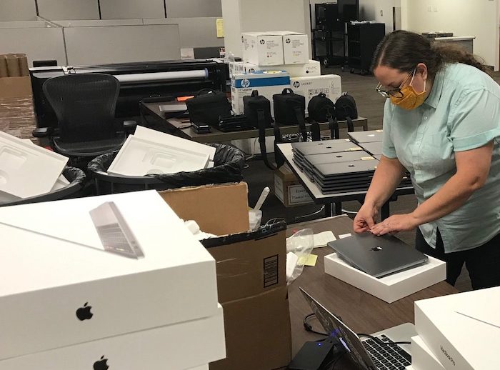 Employee processing laptop checkouts for students