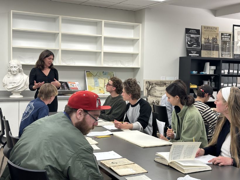 Rare books librarian Lyuba Basin teaching & presenting in front of a group of students looking at rare book materials.