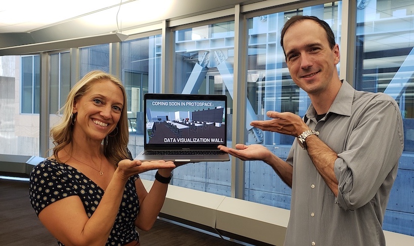Two library employees holding a laptop 