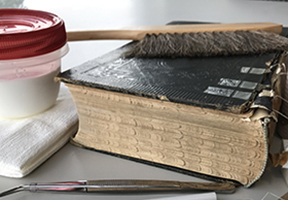 image of old book along with materials and supplies used to repair it