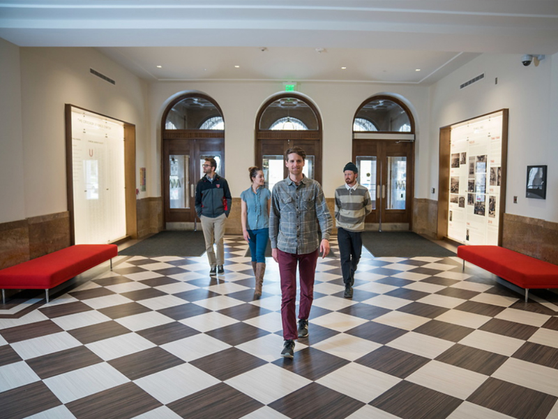 Undergraduate students walk down a campus building hallway