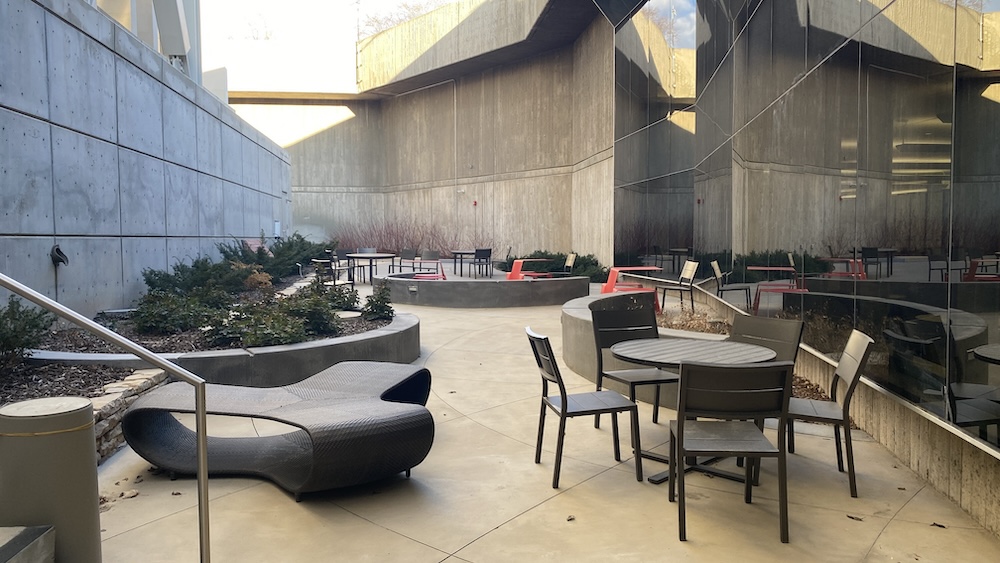 seating area with tables, chairs, nestled in an alcove in between buildings