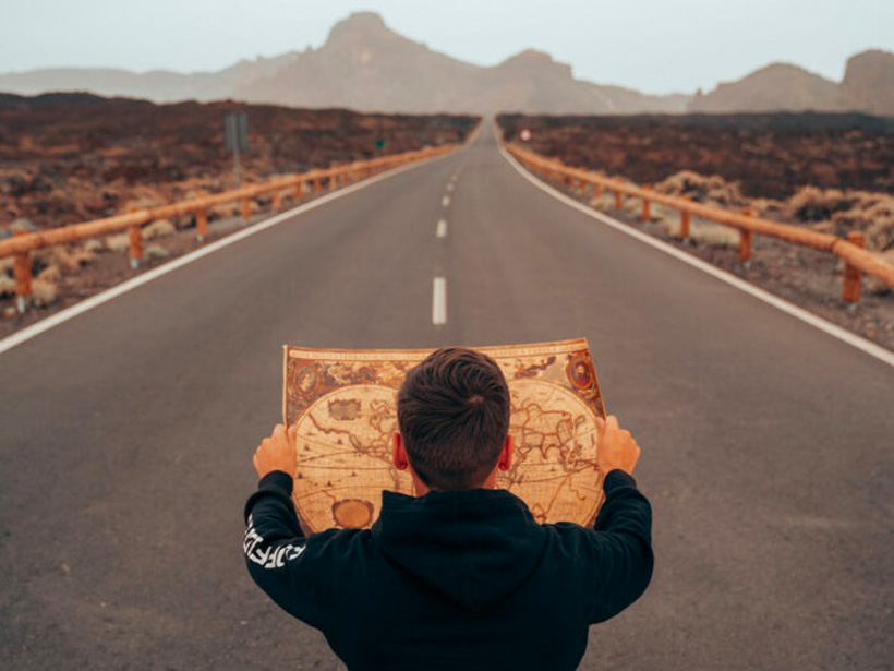 Person holding a map looking ahead to a road