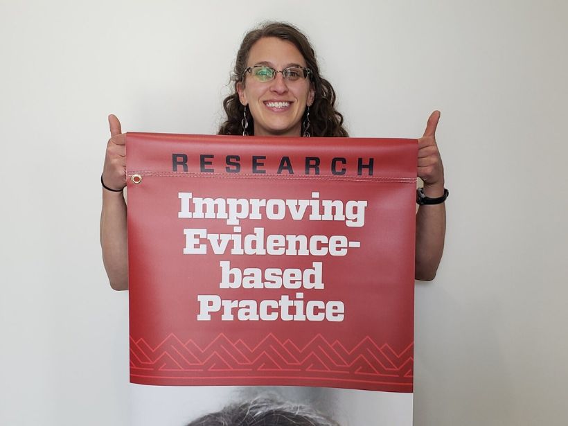 Tallie Casucci holding a banner that says research improving evidence based practice