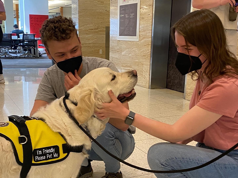 two students petting a happy dog