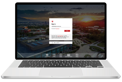 a mac laptop that has an aerial view of campus in the background of a login window